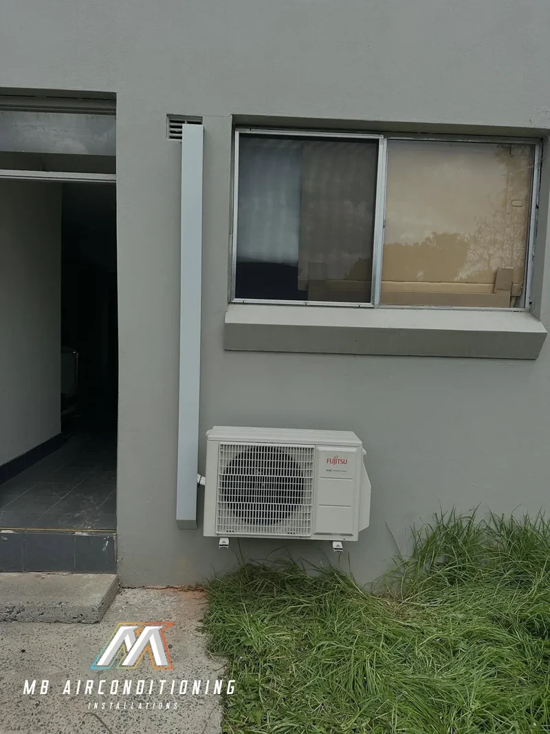 Outdoor condenser mounted on a rendered wall with room around it for maintenance